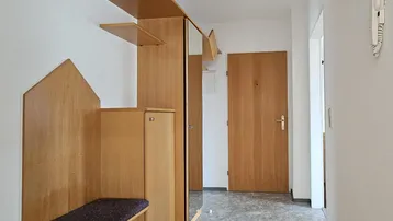 Heller Eingangsbereich mit praktischer Garderobe, Spiegel und Holzelementen für eine einladende Atmosphäre.