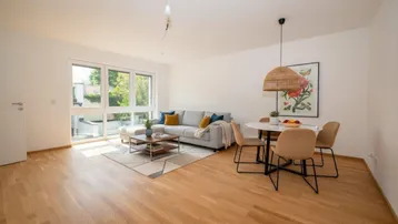 Helles, offenes Wohn-Esszimmer mit Parkettboden, großen Fenstern und Zugang zur Terrasse.