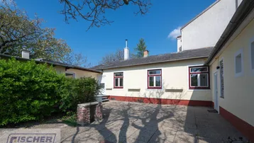 Gepflasterter Innenhof mit Gebäudefassaden und einem Baum, ideal für entspannte Stunden im Freien.
