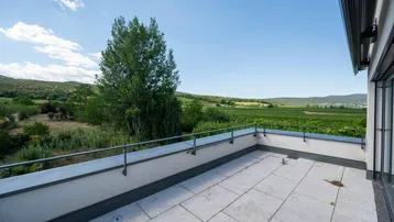 Große Dachterrasse mit Fliesenboden und weitem Blick über Weinberge und Landschaft.
