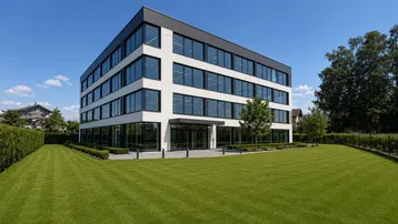 Modernes Bürogebäude mit großen Glasfassaden und gepflegter Grünfläche unter blauem Himmel.