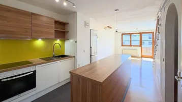 Moderne offene Küche mit Holzelementen, gelber Rückwand und integrierter Kochinsel.