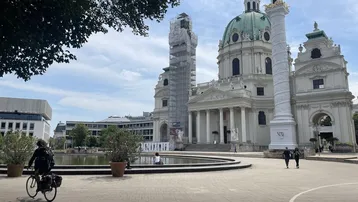 Prunkvolles historisches Gebäude mit Kuppel und Säulen, teilweise eingerüstet, an einem belebten öffentlichen Platz.
