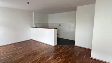 Heller Wohnbereich mit Parkettboden und offener Gestaltung zur Küche, ideal für modernes Wohnen.