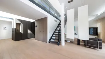 Geräumiges, modernes Wohnzimmer mit offener Galerie, Holzfußboden und integrierten Schränken.