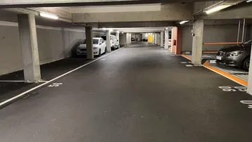 Geräumige Tiefgarage mit markierten Stellplätzen, Betonpfeilern und heller Beleuchtung.