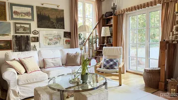 Gemütliches Wohnzimmer mit bequemen Sofas, vielen Bildern an der Wand und Zugang zum Garten.