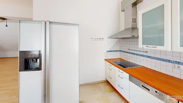 Funktionale Küche mit weißen Schränken, Holzarbeitsplatte und integrierten Geräten wie Kühlschrank und Geschirrspüler.