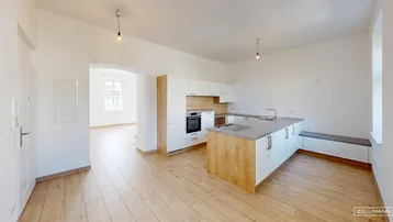 Moderne offene Küche mit hellen Holzfronten, weißer Arbeitsplatte und Holzboden.