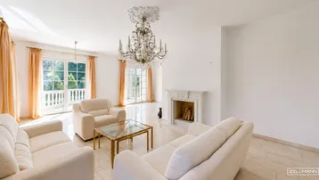Helles Wohnzimmer mit elegantem Kronleuchter, dekorativem Kamin und Zugang zu einem Balkon.