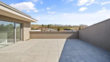 Helle Terrasse mit Schiebetüren und Blick auf die umliegende Landschaft unter blauem Himmel.