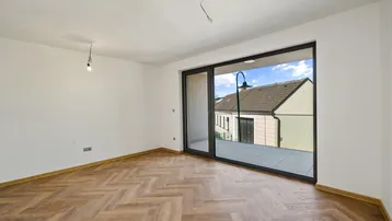 Geräumiges Wohnzimmer mit Fischgrätparkett und Zugang zu einem Balkon mit Blick auf die Nachbarschaft.