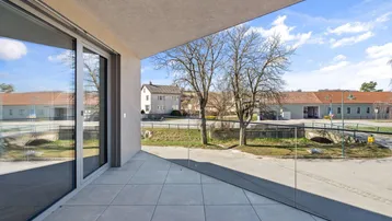 Moderner Balkon mit Fliesenboden und weitem Blick auf die Umgebung und Bäume.