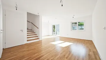 Helles, leeres Wohnzimmer mit Parkettboden und Zugang zur Terrasse, bereit für die Einrichtung.