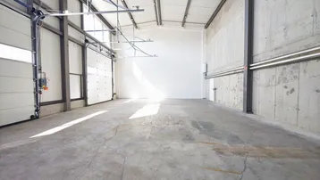 Geräumige Lagerhalle mit hohen Decken, Betonboden und großen Rolltoren für einfachen Zugang.