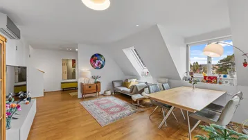 Helles Dachgeschoss-Wohnzimmer mit Essbereich, Holzboden und schrägen Wänden.