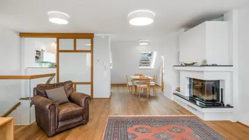 Offener Wohnbereich mit Kamin, Holzboden und Blick auf den Essbereich und die Küche.