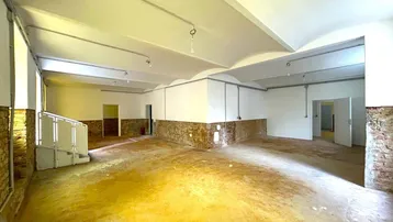 Großer, leerer Raum mit unverputzten Ziegelwänden und hohen Decken, bereit für den Ausbau.