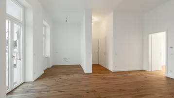 Geräumiges, helles Zimmer mit Holzboden und Zugang zu weiteren Räumen.