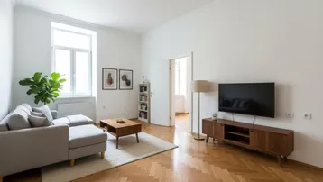 Helles Wohnzimmer mit Fischgrätparkett, modernem Sofa und TV-Möbel, das viel Tageslicht erhält.