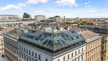 Panoramablick auf ein modernes Gebäude mit Glasdachstruktur inmitten der Stadtlandschaft.