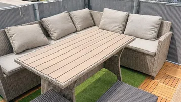 Gemütlicher Außenbereich mit Rattanmöbeln und Holzboden auf einem Balkon mit Blick auf die Nachbarschaft.