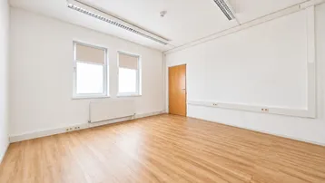 Heller Büroraum mit modernem Laminatboden, großen Fenstern und neutralen weißen Wänden.