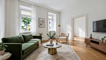 Helles Wohnzimmer mit modernem Sofa, Couchtisch und Fischgrätparkettboden, blickt auf grüne Bäume.