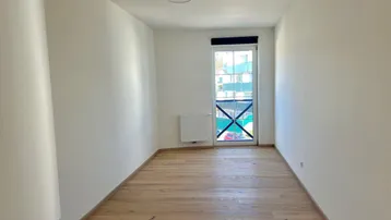 Helles Schlafzimmer mit Holzboden, weißen Wänden und französischem Balkon für frische Luft.