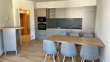 Offener Wohn- und Essbereich mit moderner Einbauküche, Holzboden und Esstisch für gesellige Runden.