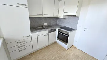 Kompakte, moderne Küche mit weißen Schränken, integriertem Backofen und Laminatboden.