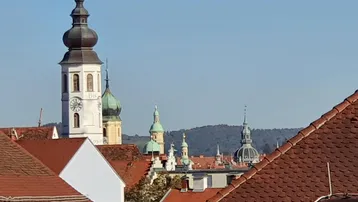 Historische Kirchtürme und Dächer der Stadt unter blauem Himmel.