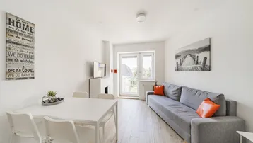 Heller Wohn- und Essbereich mit modernem Sofa, Esstisch und Zugang zum Balkon.