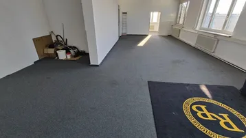 Geräumiges, leeres Büro mit grauem Teppichboden und großen Fenstern, bereit zur individuellen Gestaltung.