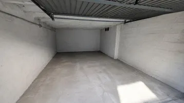 Leere Garage mit Betonboden und weiß gestrichenen Wänden, bereit zur Nutzung.