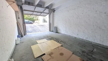 Geräumige Garage mit Betonboden und offenem Tor, bereit zur Nutzung und Lagerung.