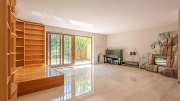 Geräumiges Wohnzimmer mit Steinkamin, Klavier und Zugang zu einem Außenbereich.