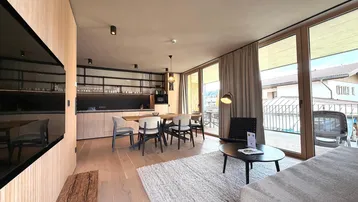 Offener Wohn-Essbereich mit moderner Küche, Holzboden und Zugang zum Balkon.