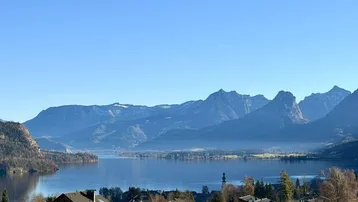 Panoramablick auf einen malerischen See, umgeben von majestätischen Bergen und einem charmanten Dorf.