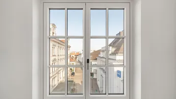 Fenster mit Sprossen und Blick auf die umliegenden Gebäude der Stadt.