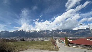 Panoramablick auf die Stadt und schneebedeckte Berge unter einem weiten blauen Himmel.