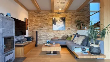 Gemütliches Wohnzimmer mit Holzboden, Kaminofen und dekorativer Steinwand.