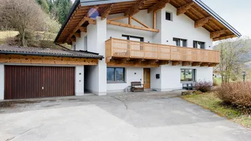 Modernes Einfamilienhaus im alpinen Stil mit Holzdetails, Balkon und integrierter Garage.