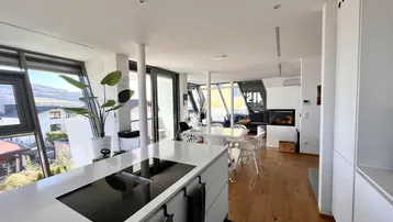 Offener Wohn- und Essbereich mit moderner Küche, Kamin und Panoramablick.