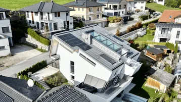 Moderne Architektur mit Photovoltaikanlage und Pool in grüner Umgebung.