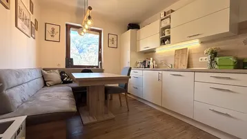 Moderne Küche mit Essbereich, Holzboden und Fenster mit Bergblick, ideal für gemütliche Mahlzeiten.