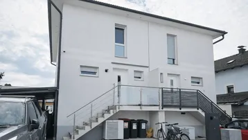 Modernes weißes Doppelhaus mit zwei separaten Eingängen und Außentreppen.