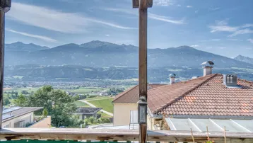 Panoramablick von einem Balkon auf eine weite Berglandschaft und umliegende Häuser.
