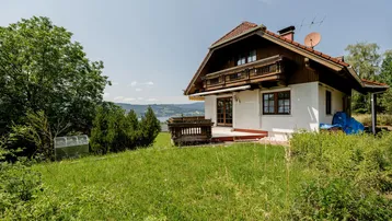 Charmantes Haus mit traditioneller Architektur, Balkon und weitem Blick auf den See und die umliegende Landschaft.
