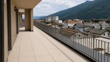 Langer Balkon mit Fliesenboden, Metallgeländer und weitem Blick über die Stadt und Berge.